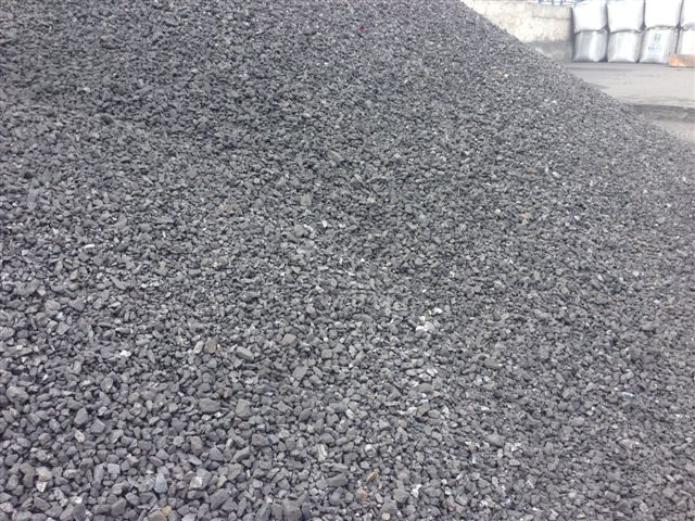 Pile of crushed stone gravel used in construction and landscaping projects, showing various sizes of dark gray rocks.