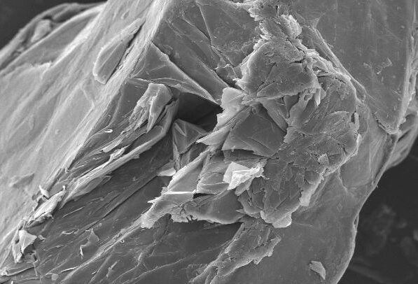 Scanning electron microscope image showing a close-up view of a mineral surface with distinct layers and textures, scale bar indicating 100 micrometers.