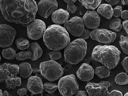 Scanning electron microscope (SEM) image showing a dense arrangement of spherical particles, demonstrating surface texture and morphology at a magnification of 53.5x. The image highlights the intricate details of the particles, useful for materials science and nanotechnology research.