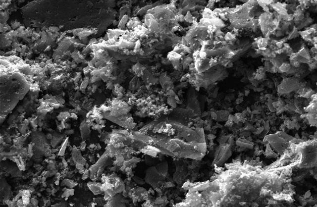 Close-up view of a granular material under a microscope, showcasing intricate textures and structures. The image highlights the details of the surface morphology, useful for studies in materials science and nanotechnology.