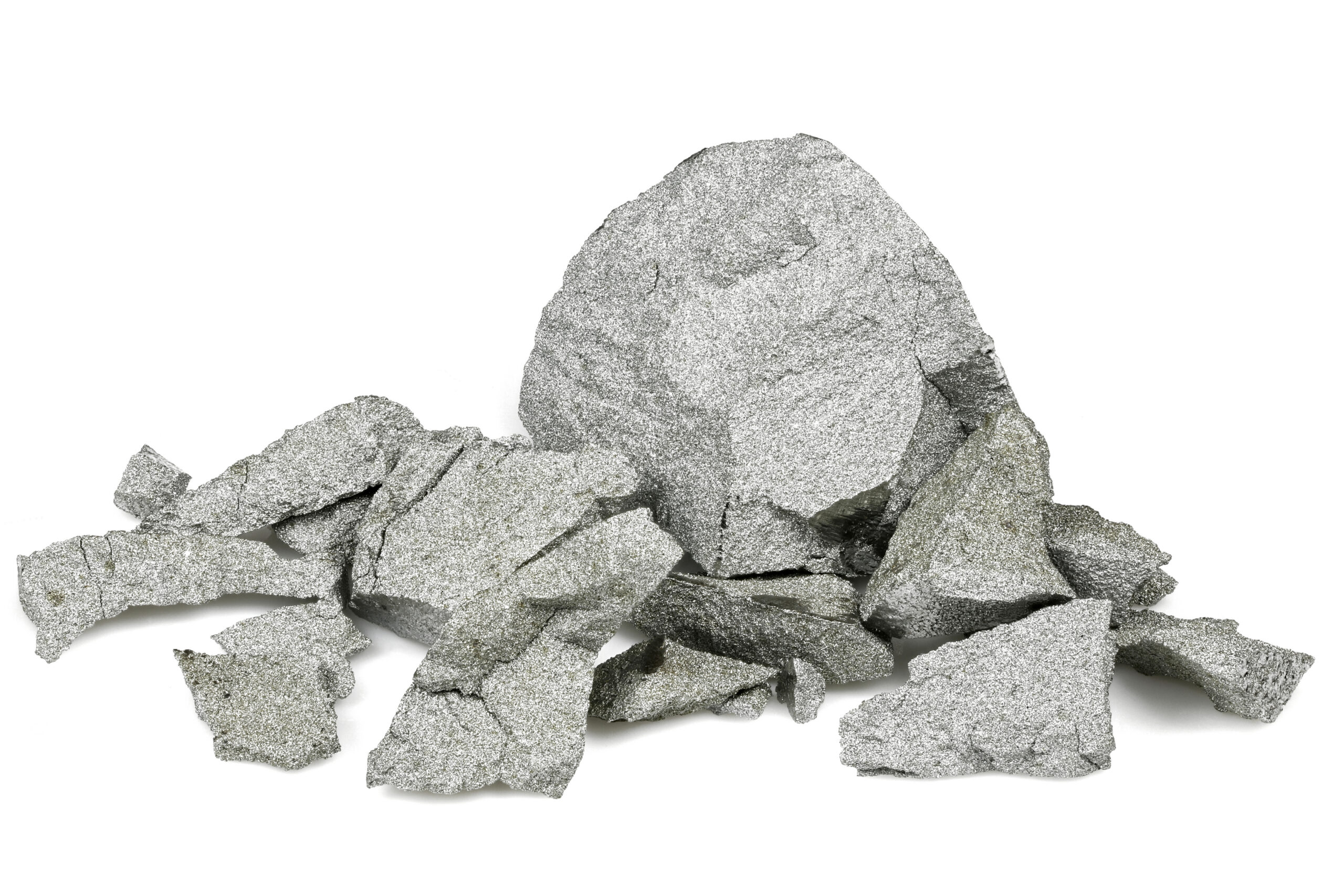 Chunky silver metal flakes and pieces scattered on a white background, showcasing their textured surface and metallic sheen.