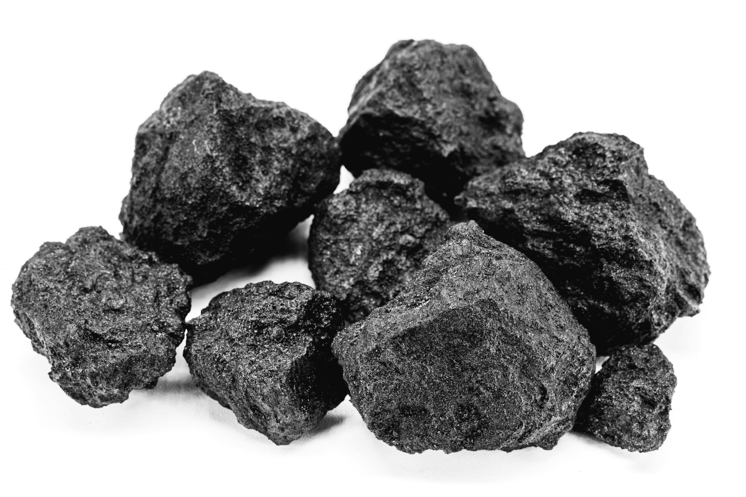 Close-up of a pile of black coal chunks on a white background, showcasing the rough texture and irregular shapes of the coal pieces. Ideal for topics related to energy, fossil fuels, or geological resources.