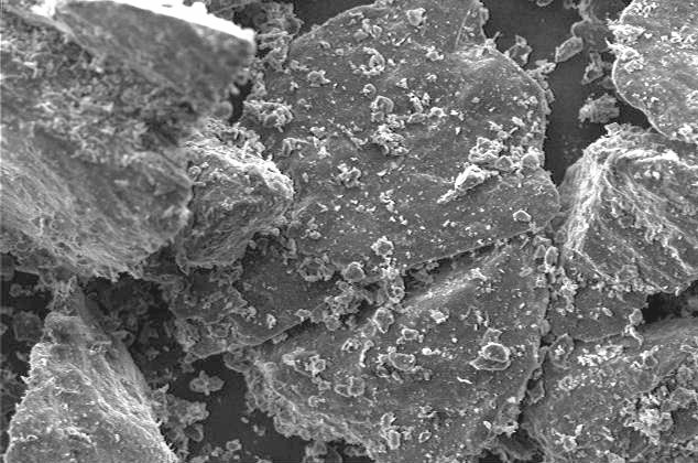 Microscopic view of mineral particles displaying jagged edges and surface textures, showcasing fine details at high magnification.