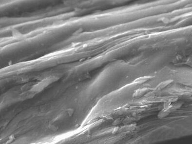 Close-up electron microscope image of layered material, showing intricate textures and structures at a magnification of 1500x. The image highlights details such as surface roughness and stratification, useful for materials science and nanotechnology research.