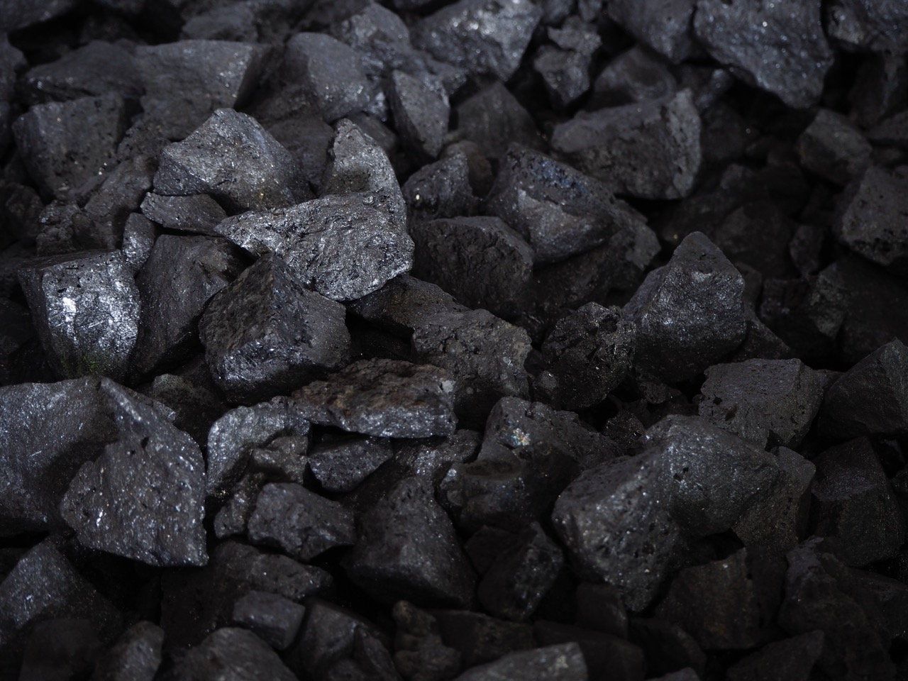 Close-up of dark, rough coal chunks, showcasing various sizes and textures, highlighting the mineral's natural characteristics and potential uses in energy production and industry.