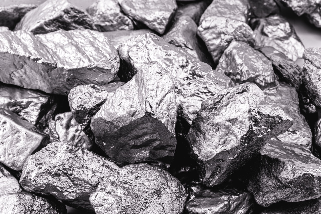 Close-up of shiny, metallic mineral rocks with varying shapes and sizes, showcasing their reflective surfaces and textures, ideal for discussions on geology, mining, or mineral resources.