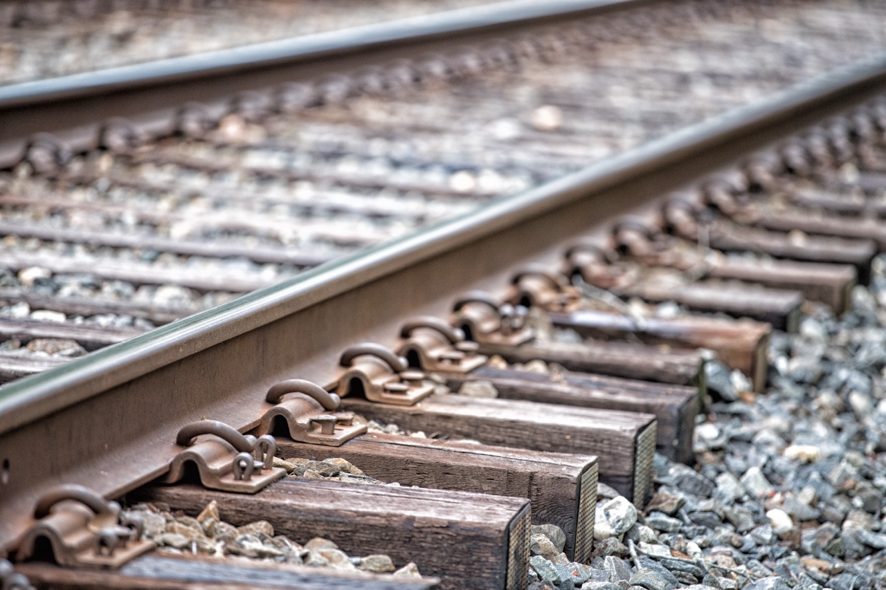 Close-up view of railway tracks showing metal rails, wooden ties, and gravel bed, illustrating the structure and materials used in train infrastructure.