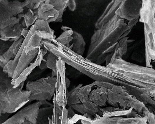 Scanning electron microscope image showing a close-up view of layered materials at 7,500x magnification. The intricate textures and structures highlight the fine details of the sample's surface morphology.