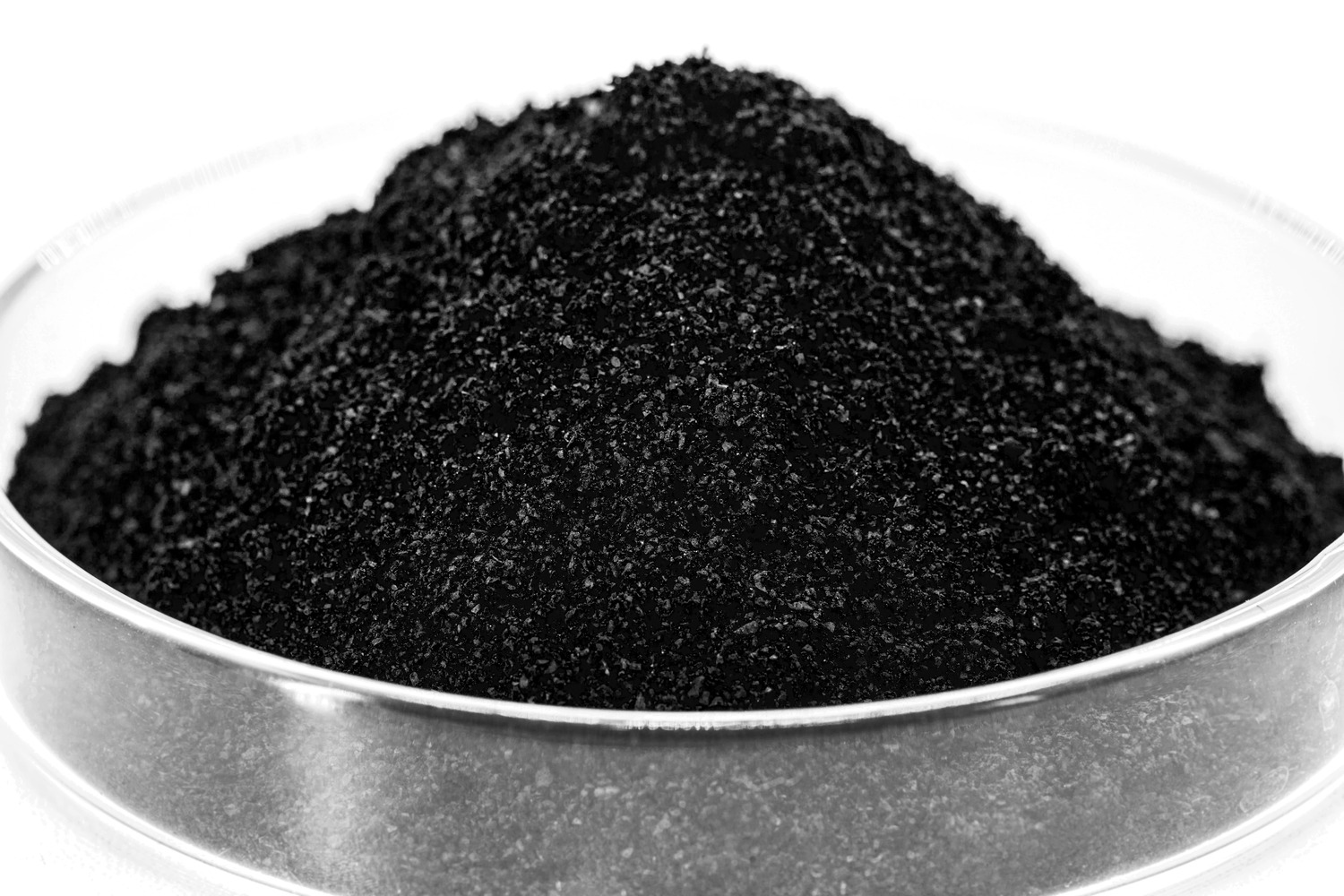 Close-up view of a mound of black powder in a silver container, showcasing its fine, granular texture suitable for various applications such as art, cosmetics, or industrial uses.