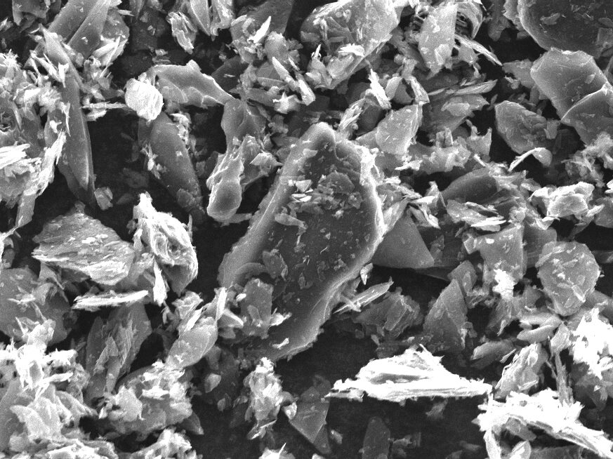 Scanning electron microscope image of carbon particles showcasing their irregular shapes and textures, highlighting the material's structure at 750x magnification. Ideal for research in materials science and carbon applications.