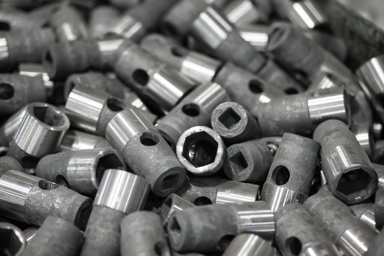 Close-up of various metal hexagonal and cylindrical fasteners stacked together, showcasing their shiny and matte finishes, commonly used in machinery and construction.