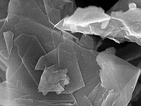 Close-up scanning electron microscope image of thin, layered mineral crystals showcasing their intricate structure and texture.