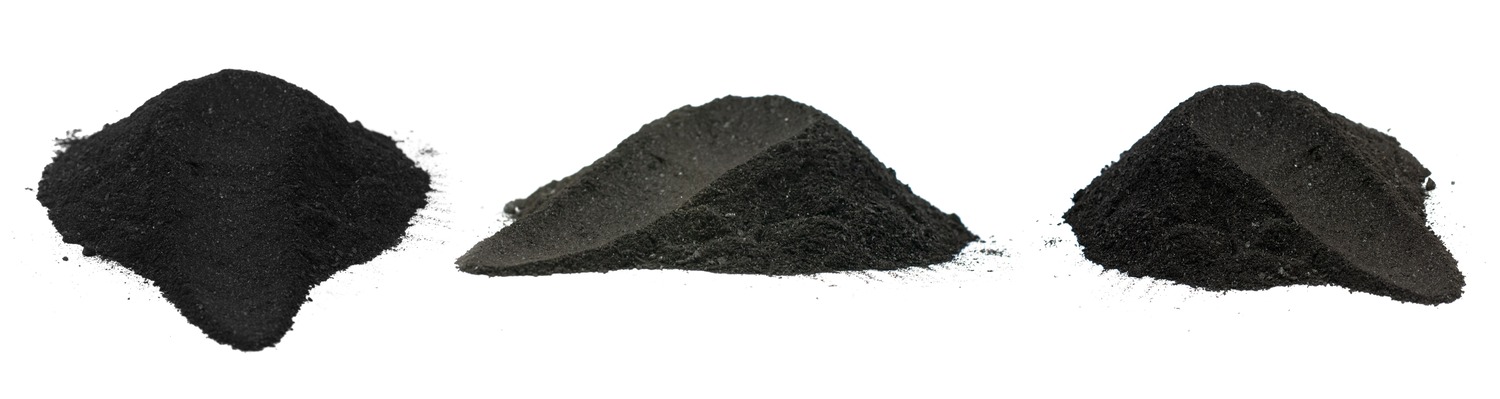 Three distinct piles of black powder are displayed on a white background, showcasing varying textures and shades. The image highlights the fine particulate nature of the materials, which could include substances like charcoal, activated carbon, or black pigment used in various applications.